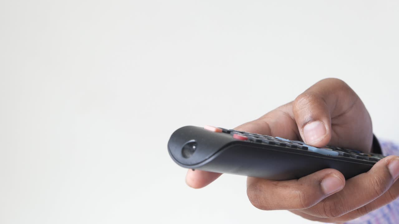 검은색 tv 리모컨을 들고 있는 손