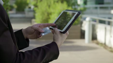 young male hands putting bank card data on tablet, paying online