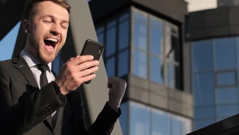 happy businessman receiving sms reading good news. joyful man-winner celebrates success