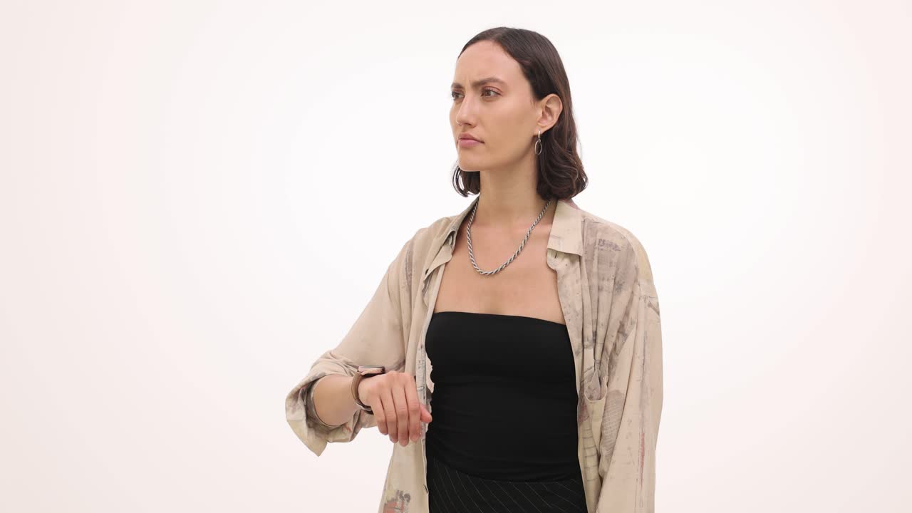 Woman checking watch impatiently and shrugging in confusion