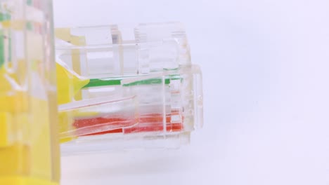 primer plano del cable ethernet de plástico amarillo girando sobre una superficie blanca, toma macro desde arriba en 4k
