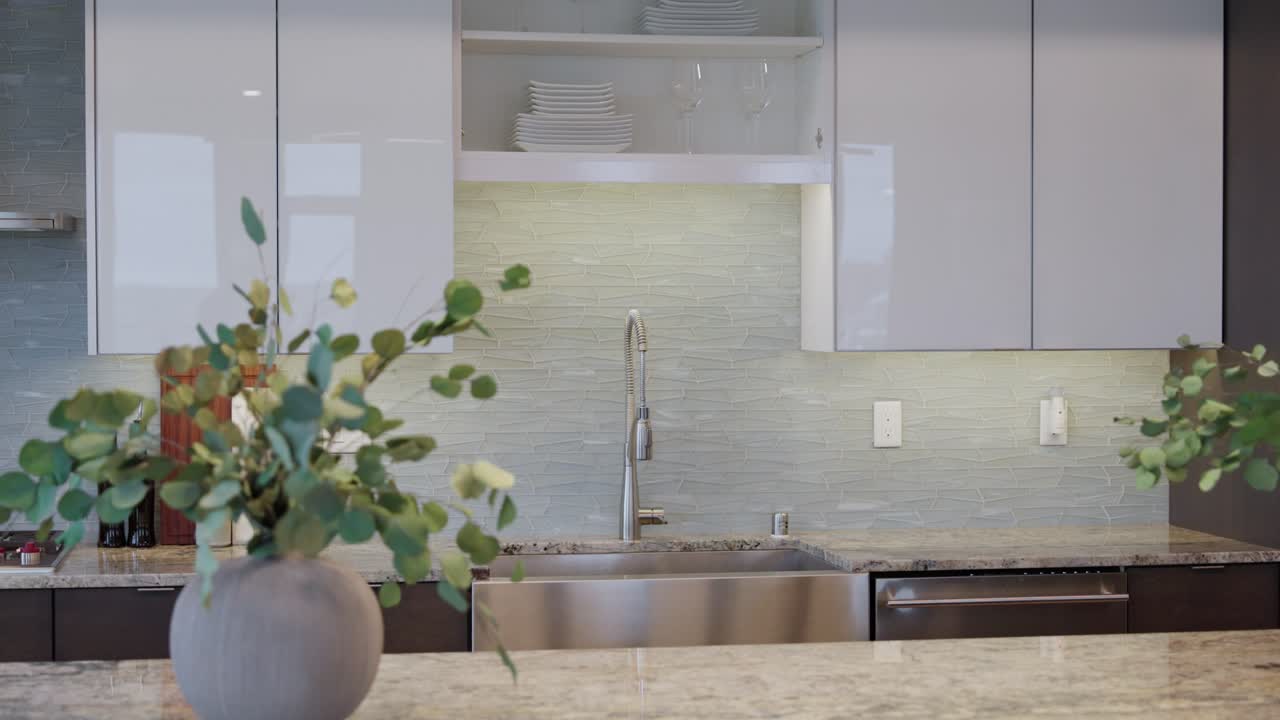 Orbiting shot of a modern kitchen sink with high-end finishes, backsplash tile, and clean decor