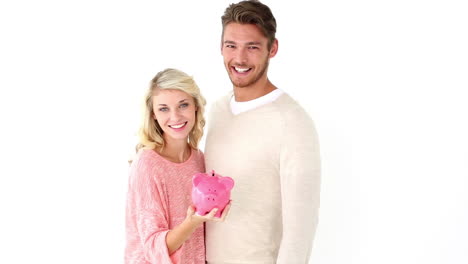 una pareja joven y atractiva con una alcancía.