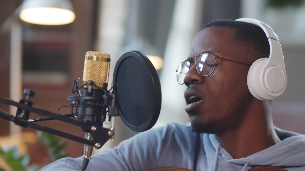 Man Singing and Playing Guitar in Home Recording Studio