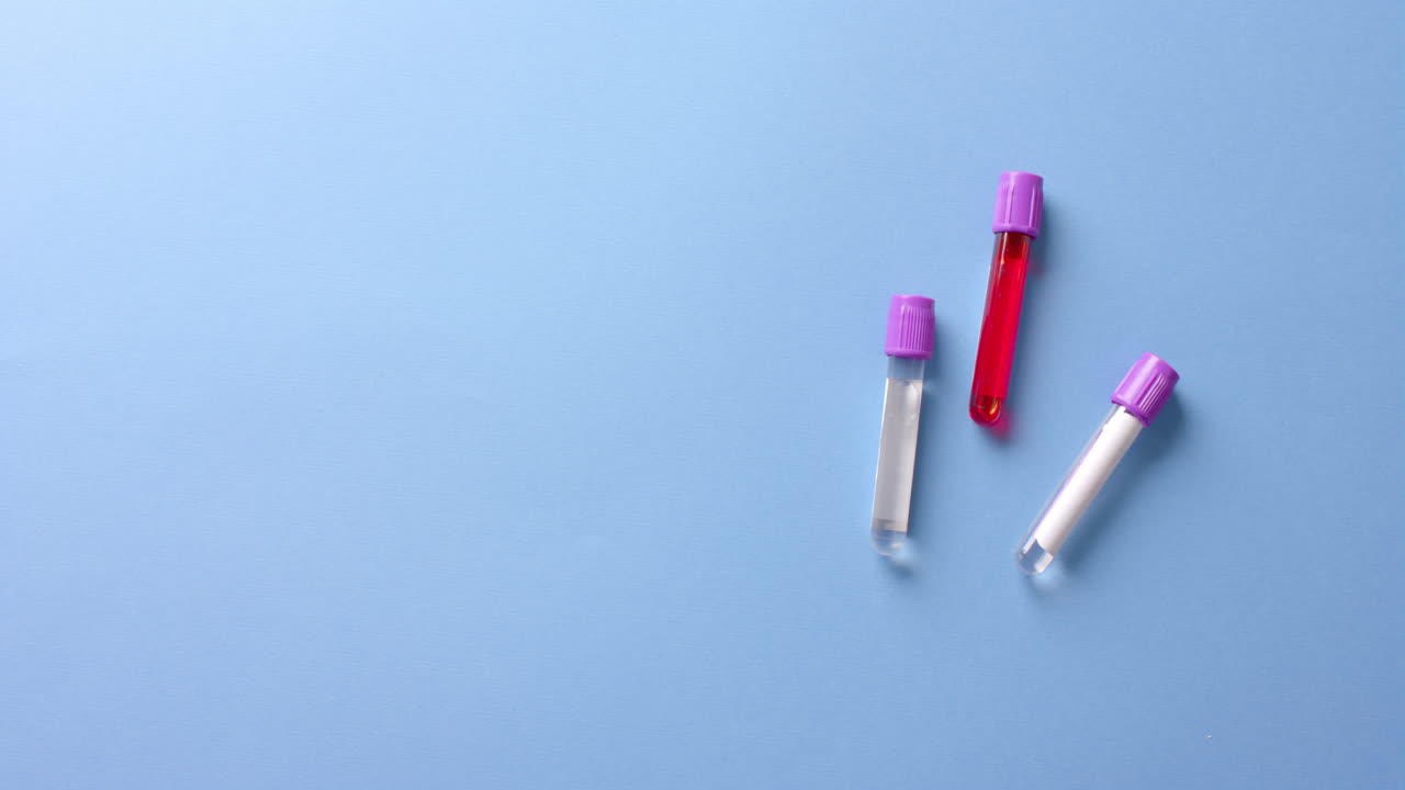 Close up of blood samples on blue background with copy space, slow motion