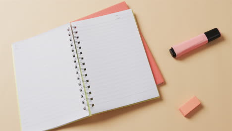 overheersende weergave van een open notebook met schoolpapier op beige achtergrond, in slow motion