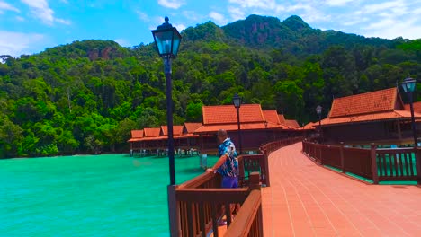 a relaxed man on a stilt of a luxury hotel looks out to sea in langkawi island