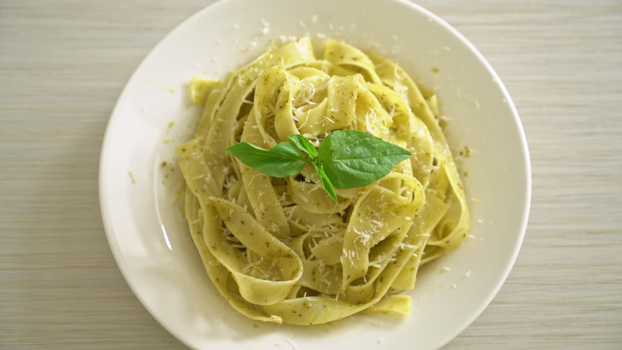 pasta fettuccine al pesto con queso parmesano encima - estilo de comida italiana