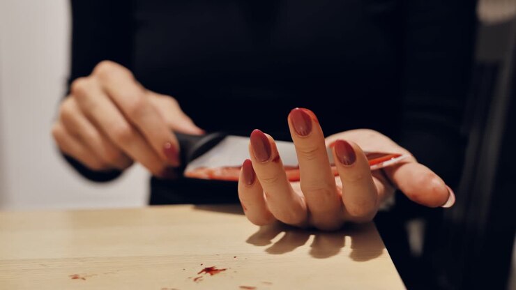 Cinematic close shot woman dragging bloody knife across her open palm