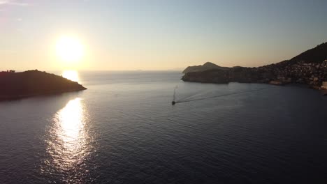 toma aérea al atardecer del mar adriático y la costa de dubrovnik con un barco.