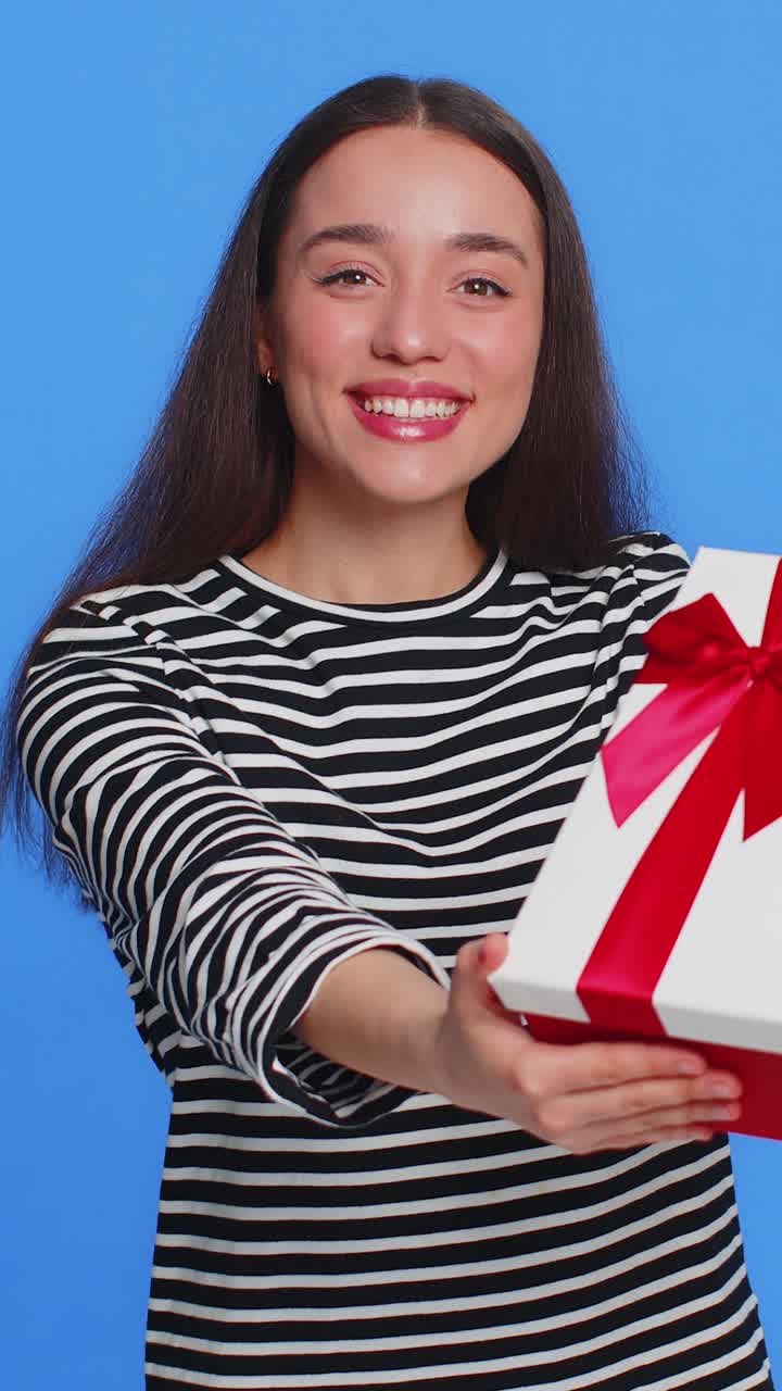 Una giovane donna sorridente presenta un regalo di compleanno una scatola di regali allunga le mani promozione vendita a sconto