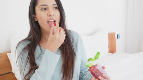 eating gummy vitamins, asian woman sitting on bed in casual clothes, at home
