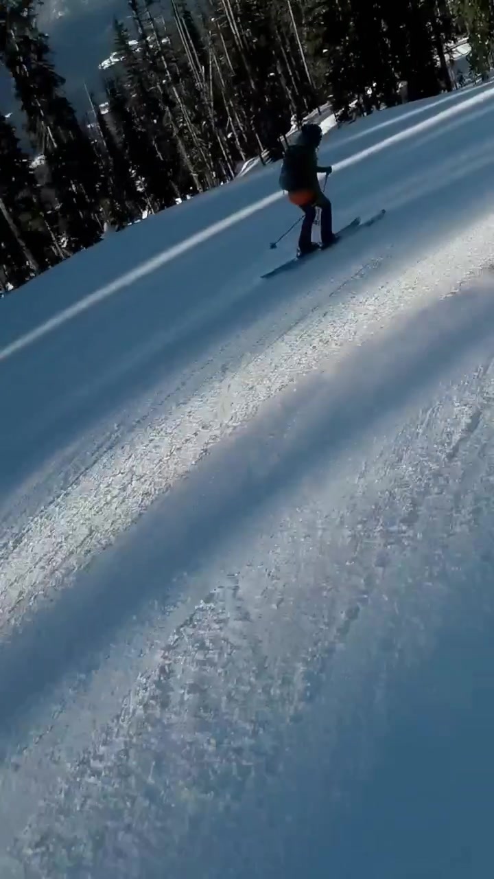 Vertical video: Starting descent, skiers and red-jacket boarder carving mountain slope to trees