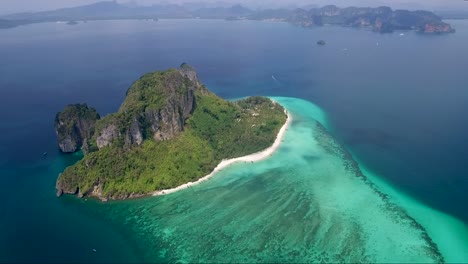 toma aérea de una pequeña isla tropical rodeada por un vasto océano colorido