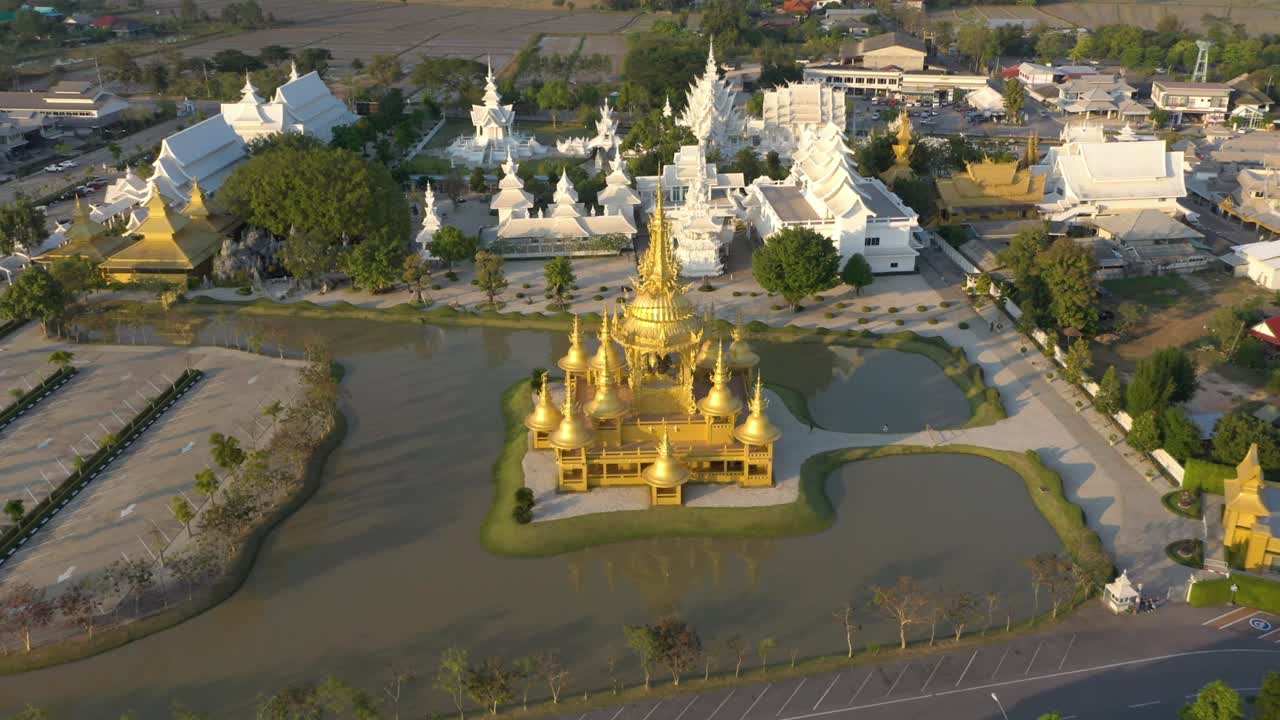 drone aéreo de wat rong khun el templo budista gigante blanco y el templo dorado con montañas y paisaje en chiang rai, tailandia