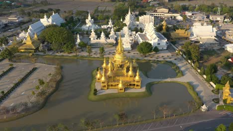 aerial drone of wat rong khun the giant buddhist white temple and golden temple with mountains and landscape in chiang rai, thailand