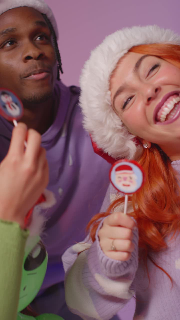 una toma vertical de estudio de video de amigos de la generación z bailando en una fiesta de navidad con sombrero de papá noel y cuernos de reno
