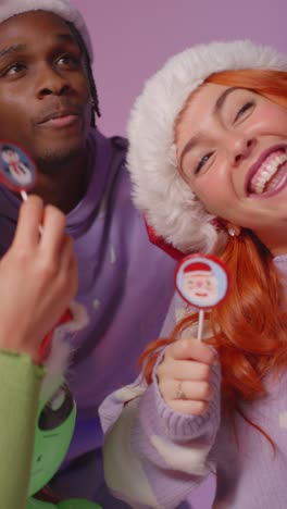 Vertical-Video-Studio-Shot-Of-Gen-Z-Friends-Dancing-At-Christmas-Party-Wearing-Santa-Hat-And-Reindeer-Antlers