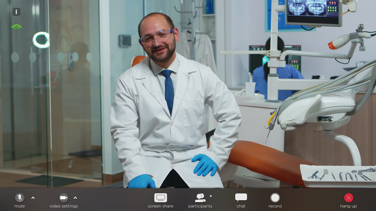 Dottore dentista che guarda la telecamera e parla con i pazienti
