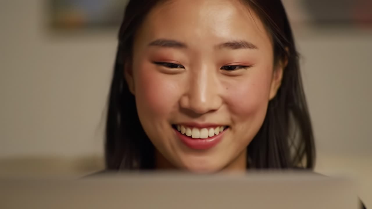 A Young Woman's Joyful Experience While Engaged with Her Laptop, Capturing the Essence of Connection and Contentment Through a Warm Smile in a Cozy Environment