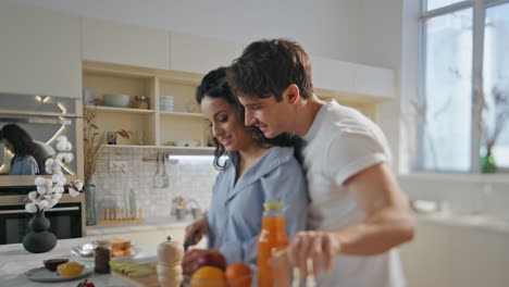 husband helping cooking breakfast to wife at kitchen close up. healthy lunch