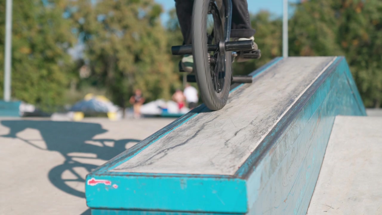Rider BMX che esegue un trick grind su una sporgenza in uno skatepark.