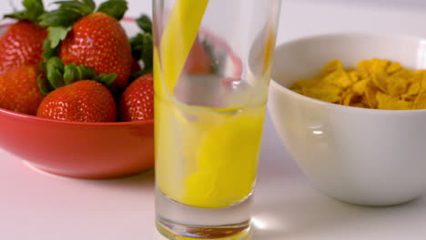 orange juice pouring into glass at breakfast table