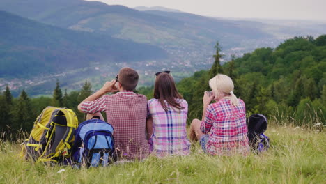 three friends rest in a picturesque place they sit around their rucksacks drink tea active lifestyle