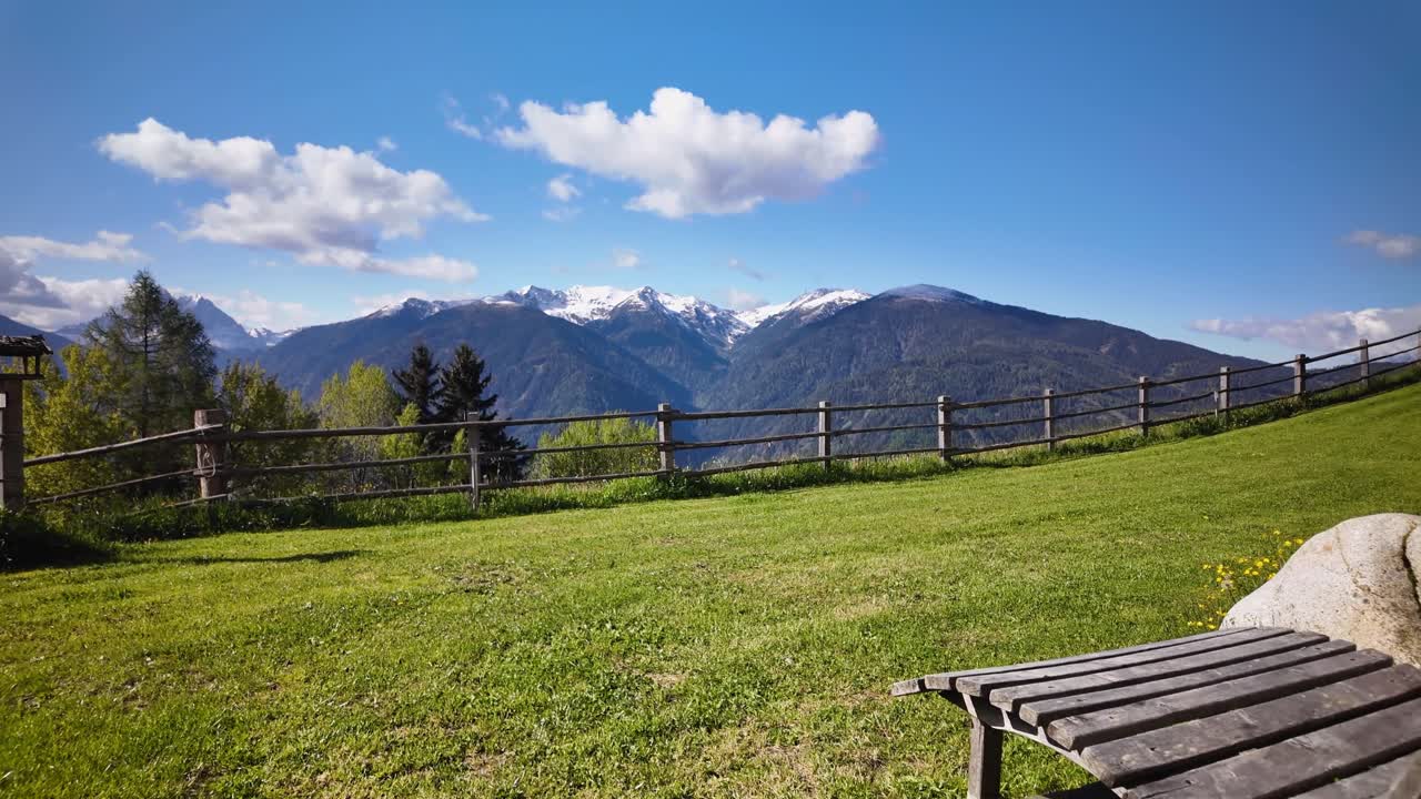 A peaceful slow-motion scene at Herolerhof in the Italian Dolomites, showing a wooden bench and lush valley with distant mountains