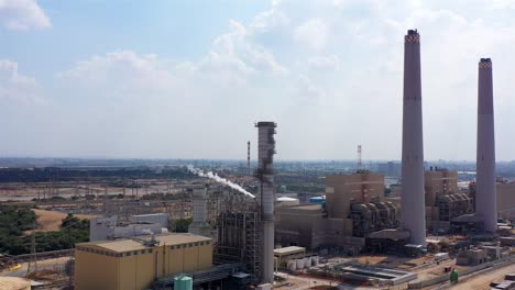 aerial footage over power plant with fuel tanks and chimneys, israel