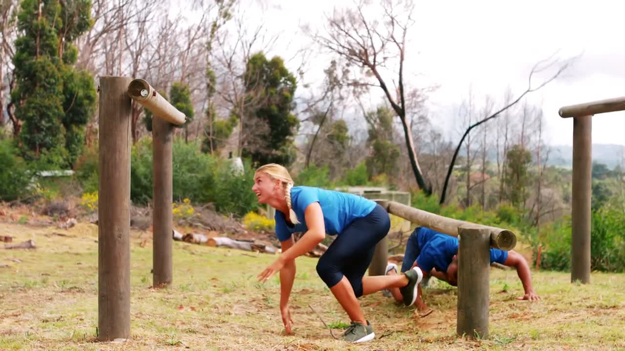 장애물 코스 도중 나무 아치 를 뛰어넘는 부부