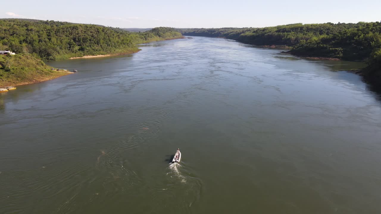 A speedboat travels upstream on the Paran&aacute; River, marking the boundary between Argentina and Paraguay, symbolizing the international connection and scenic river journey