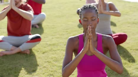 focused diverse friends practicing yoga meditation sitting in sunny garden, slow motion