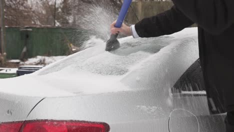 a man scraping ice off the car on a winter day - close up shot