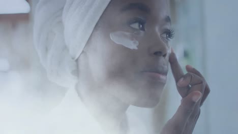 animation of african american woman using cream on face over light spots