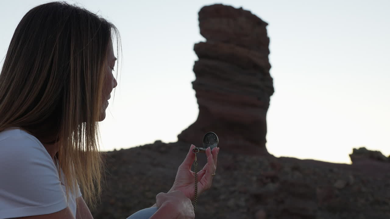 woman looking at an antique compass in a volcanic landscape with the Roques de Garcia behind her