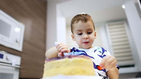 adorable toddler boy chewing his food carefully. low angle view at the baby eating a big cake with jelly top.