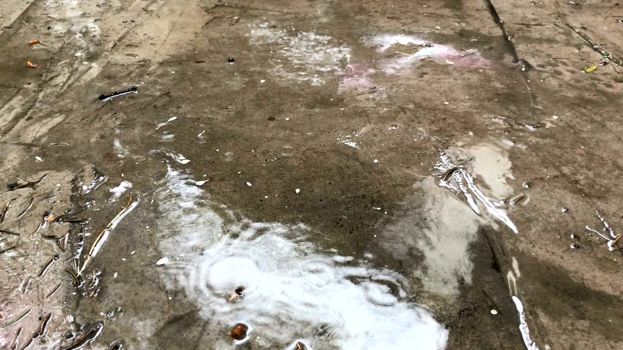 капли дождя капают на беспорядочный бетон.