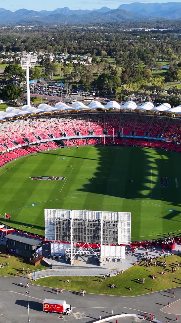 High angle drone shot of a professional sports arena with red seating and green turf.
