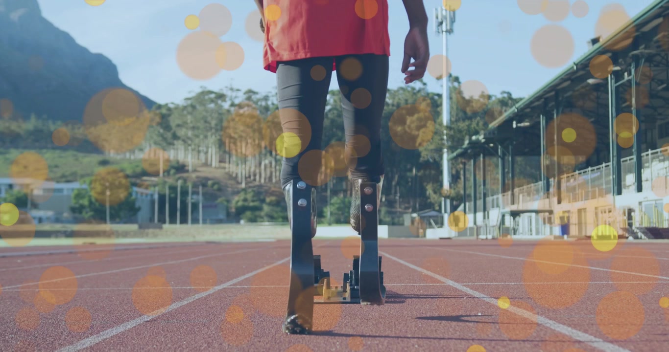 Mannlig tenåringsutøver går bort til startblokkene, justerer piggskoene og forbereder seg på sprint med bokeh-effekt.