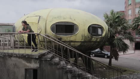 urban explorer asian girl walking upstairs to abandoned ufo-shaped house