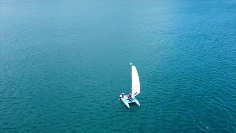 a aerial view of a small sailboat in the blue of the caribbean waters on a sunny day