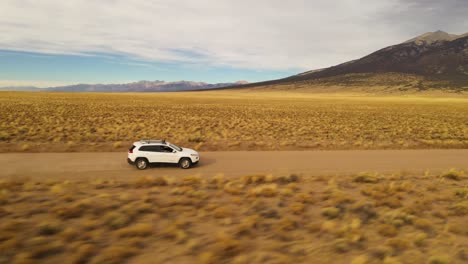 car driving on mountain valley dirt road fly over aerial shot 4k