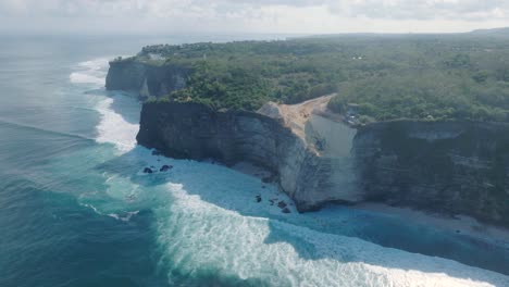 high angle drone video of environmental destruction of the limestone cliffs near pura luhur uluwatu temple, bali indonesia, with excavators, massive earth clearing, and polluted ocean