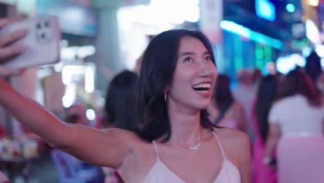 young woman taking a selfie at a vibrant street festival at night