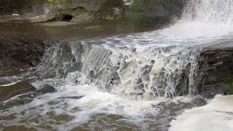 Peaceful-woodland-forest-splashing-rapid-foaming-waterfall-slow-motion-flowing-paradise-wilderness-tilt-down