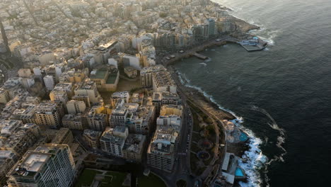 aerial tilt shot overlooking the cityscape of qui-si-sana, sunset in sliema, malta