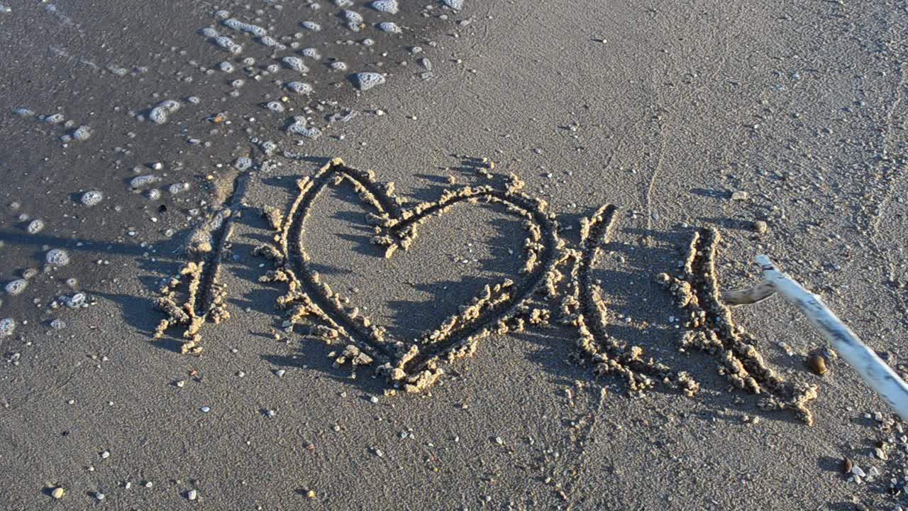 Love sign on sand, the beach. Shooting on the beach
