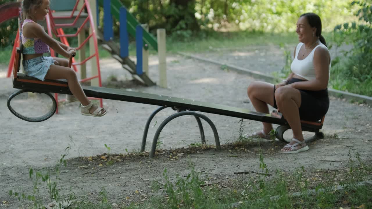 madre y hija embarazadas jugando en el columpio en el parque