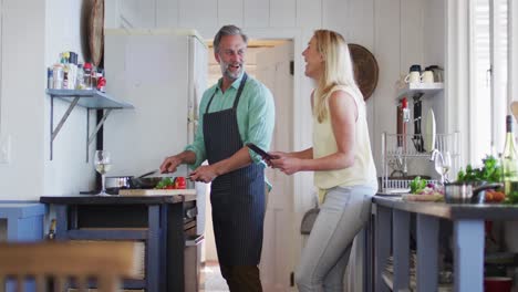 feliz pareja caucásica madura cocinando juntos y usando tableta